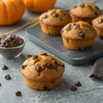 Close-up of Pumpkin Chocolate Chip Muffins on a gray surface.