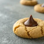 peanut butter blossom cookie with chocolate kiss center on gray surface