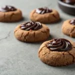 Chocolate thumbprint cookies with jam centers on gray surface