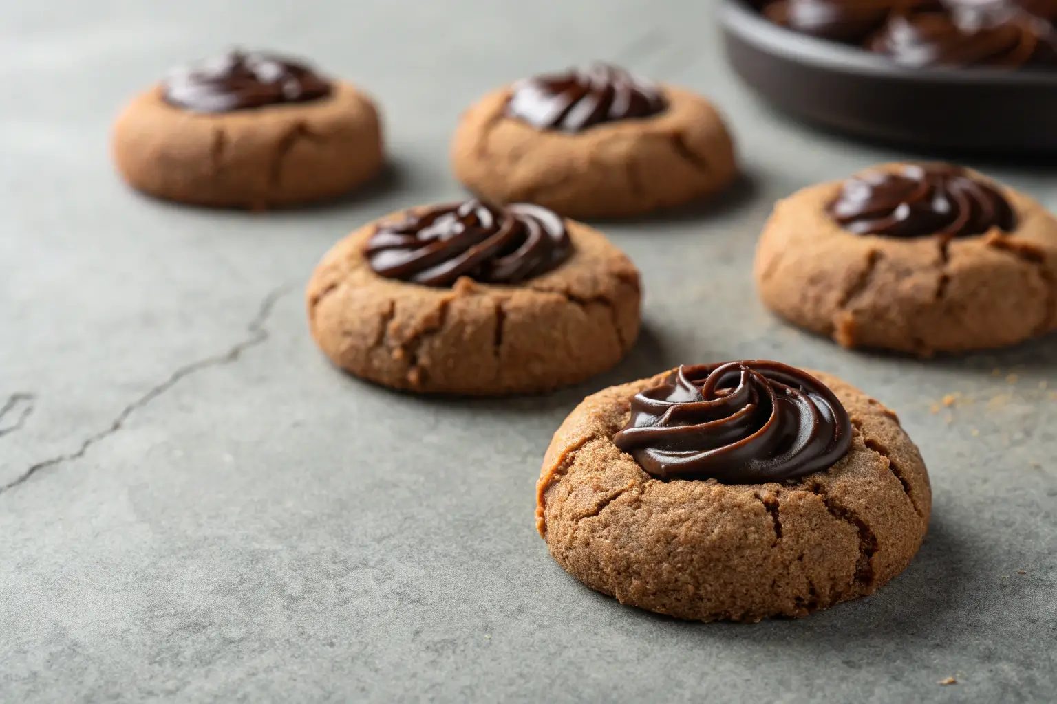 Chocolate thumbprint cookies with jam centers on gray surface