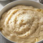Creamy Alfredo sauce in a bowl with Parmesan and pepper